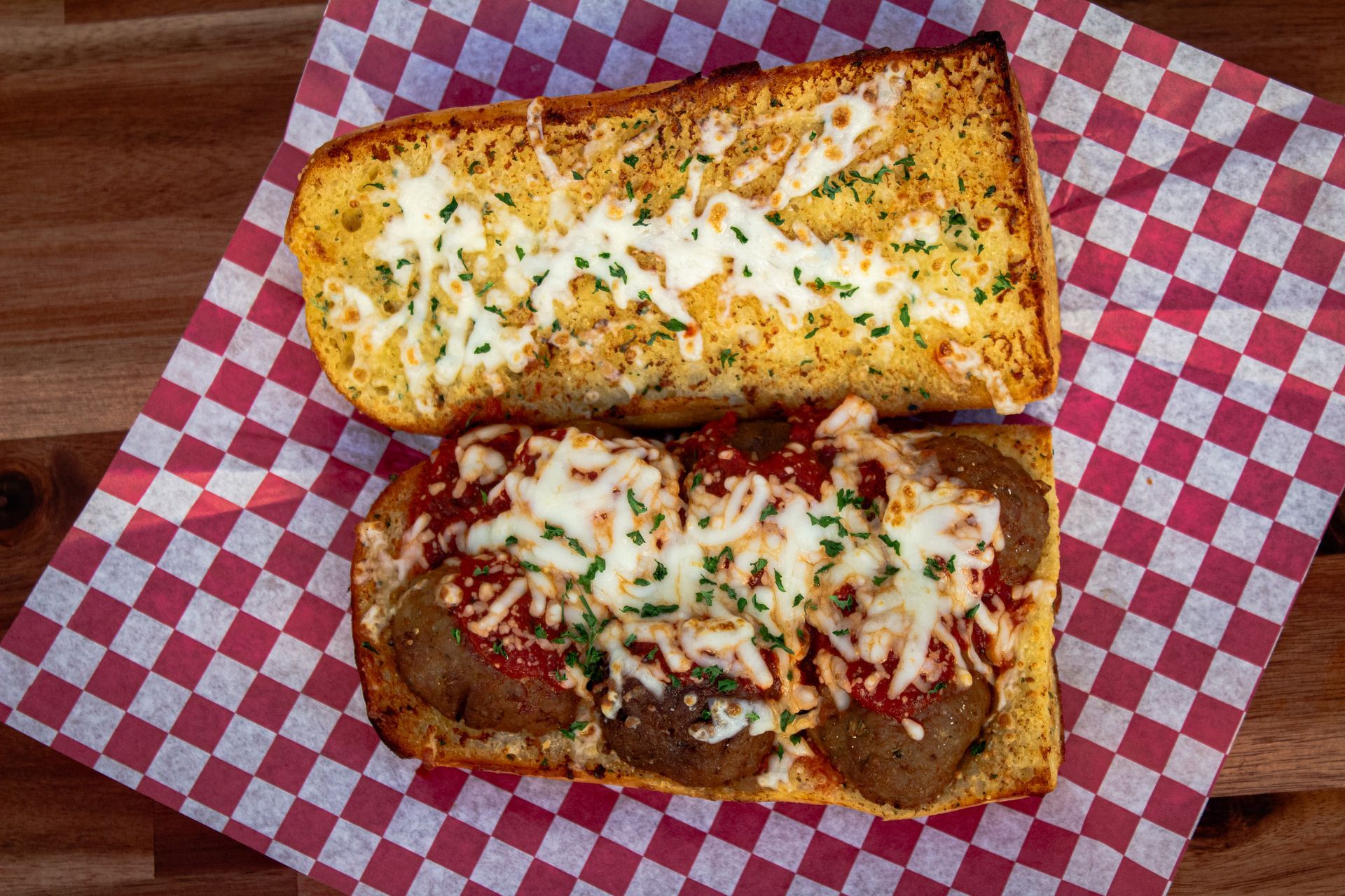 Meatball sub on toasted garlic bread, red checkered paper.