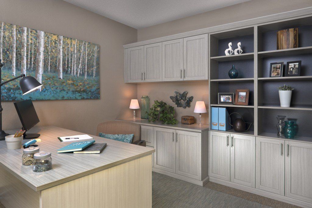 a home office with a desk , shelves , and a painting on the wall .