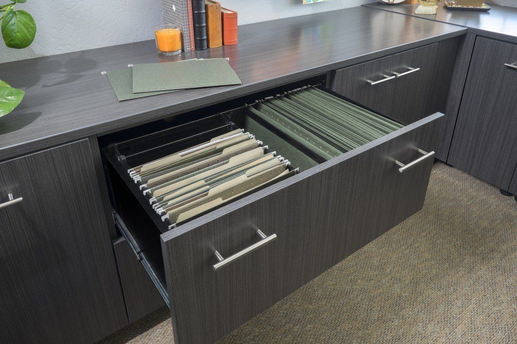 a drawer filled with binders is open on a desk