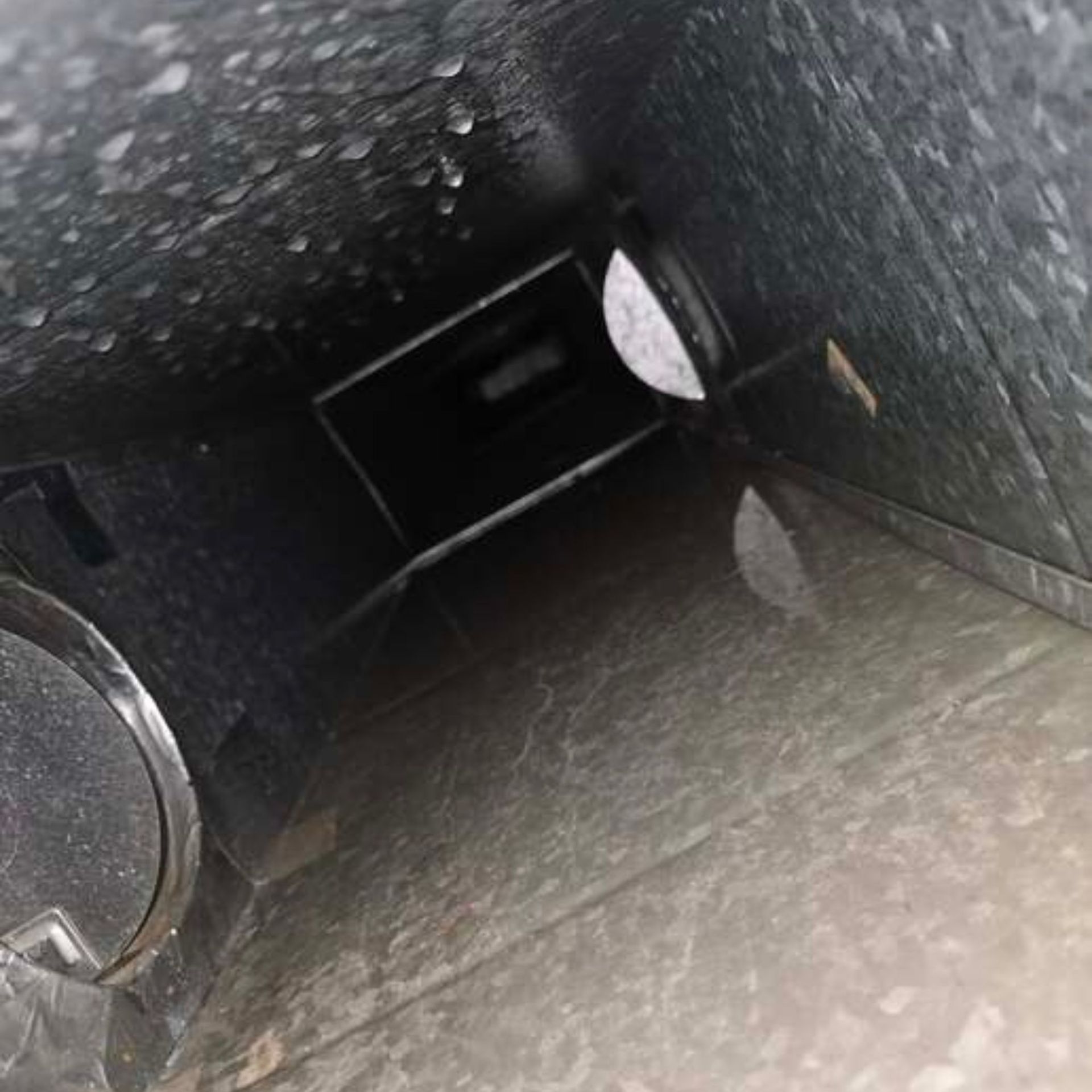 Duct Wrangler, LLC - Inside of a dark duct with rectangular opening. Metallic, dusty surfaces.