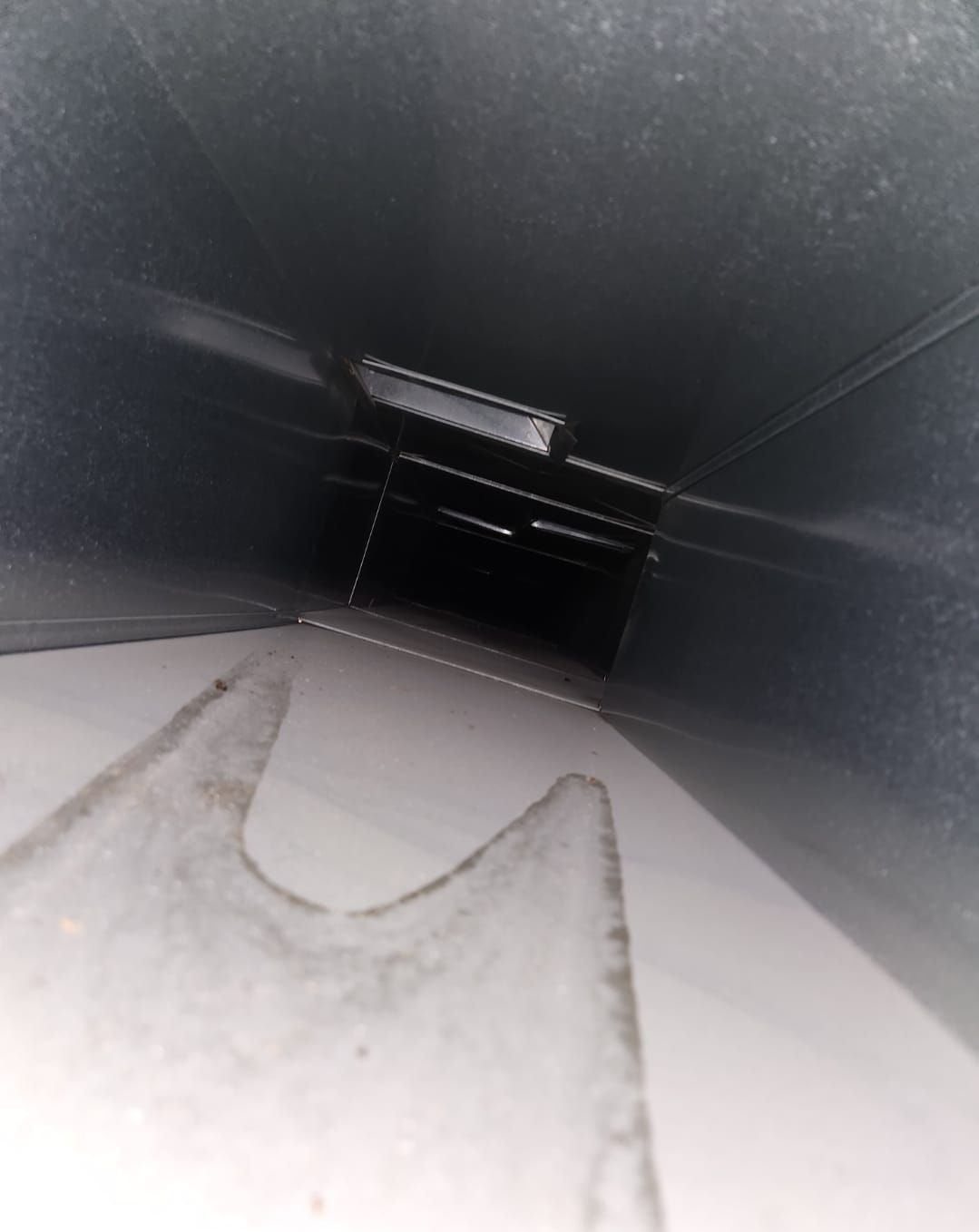 Looking down a metal duct with a white arrow pointing to the right