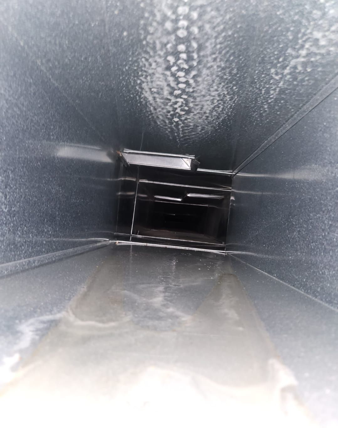 A close up of a metal duct with water coming out of it.