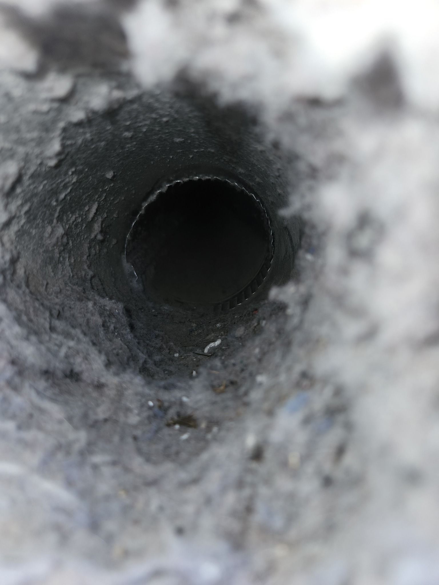 A close up of a hole in a pipe with a white background.