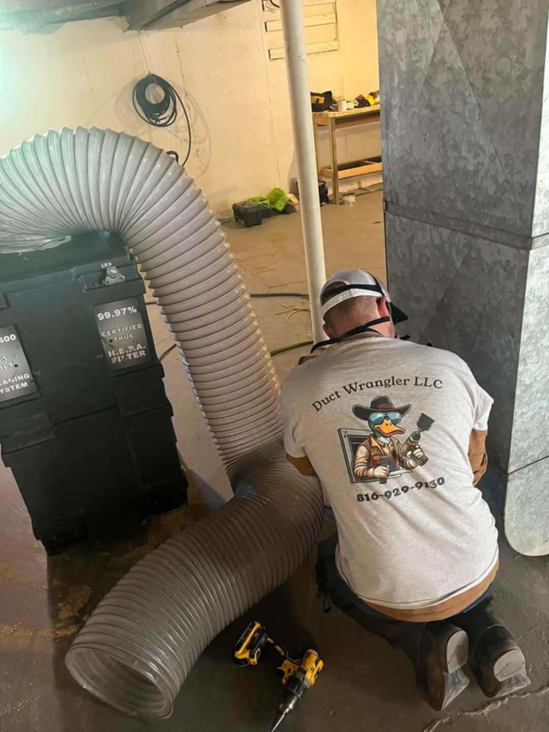 A man is kneeling down next to a large hose in a room.