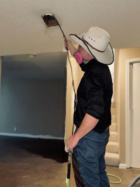 A man wearing a cowboy hat is working on a ceiling