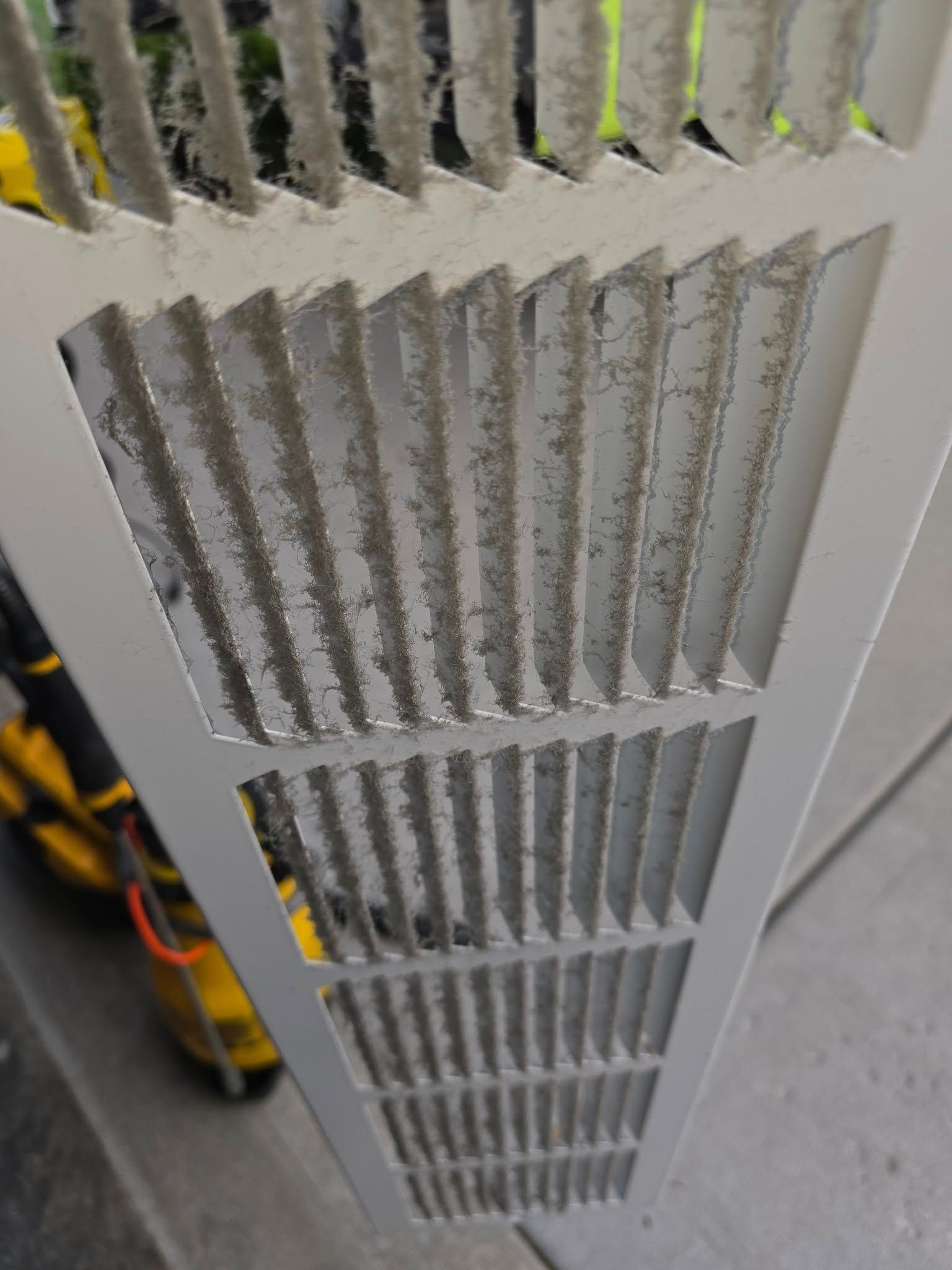 A close up of a dirty air vent on a wall.