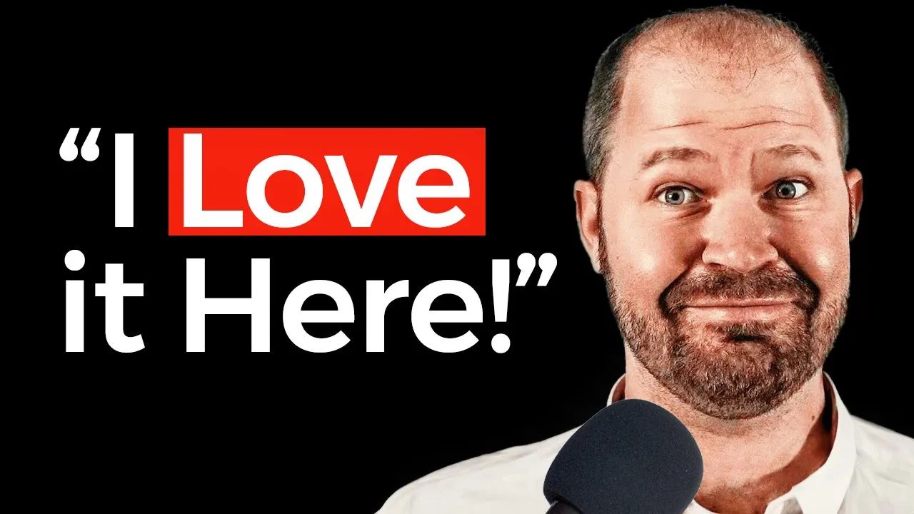 A man with a beard is holding a microphone and saying i love it here.