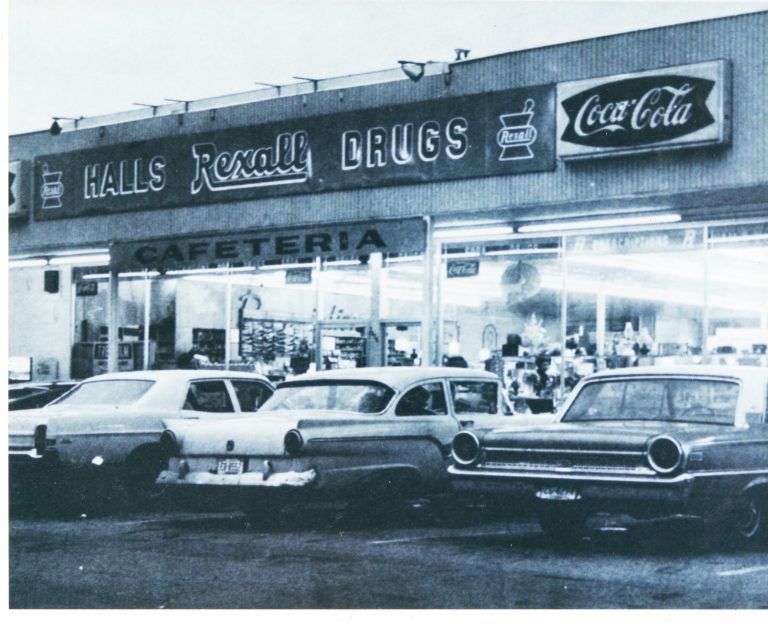 halls business and professional association photo of Halls Rexall Drugs/Halls Drugstore & Cafeteria in black and white with cars parked outside