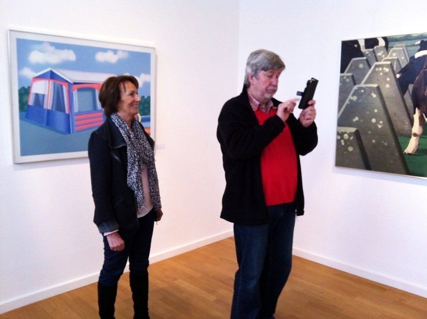 Ein Mann fotografiert eine Frau vor einem Gemälde