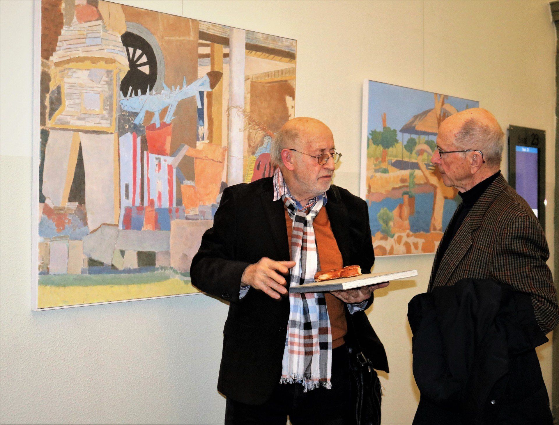 Zwei Männer stehen vor einem Gemälde und unterhalten sich