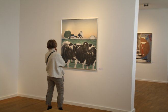 Eine Frau betrachtet ein Gemälde von Kühen auf einer Weide