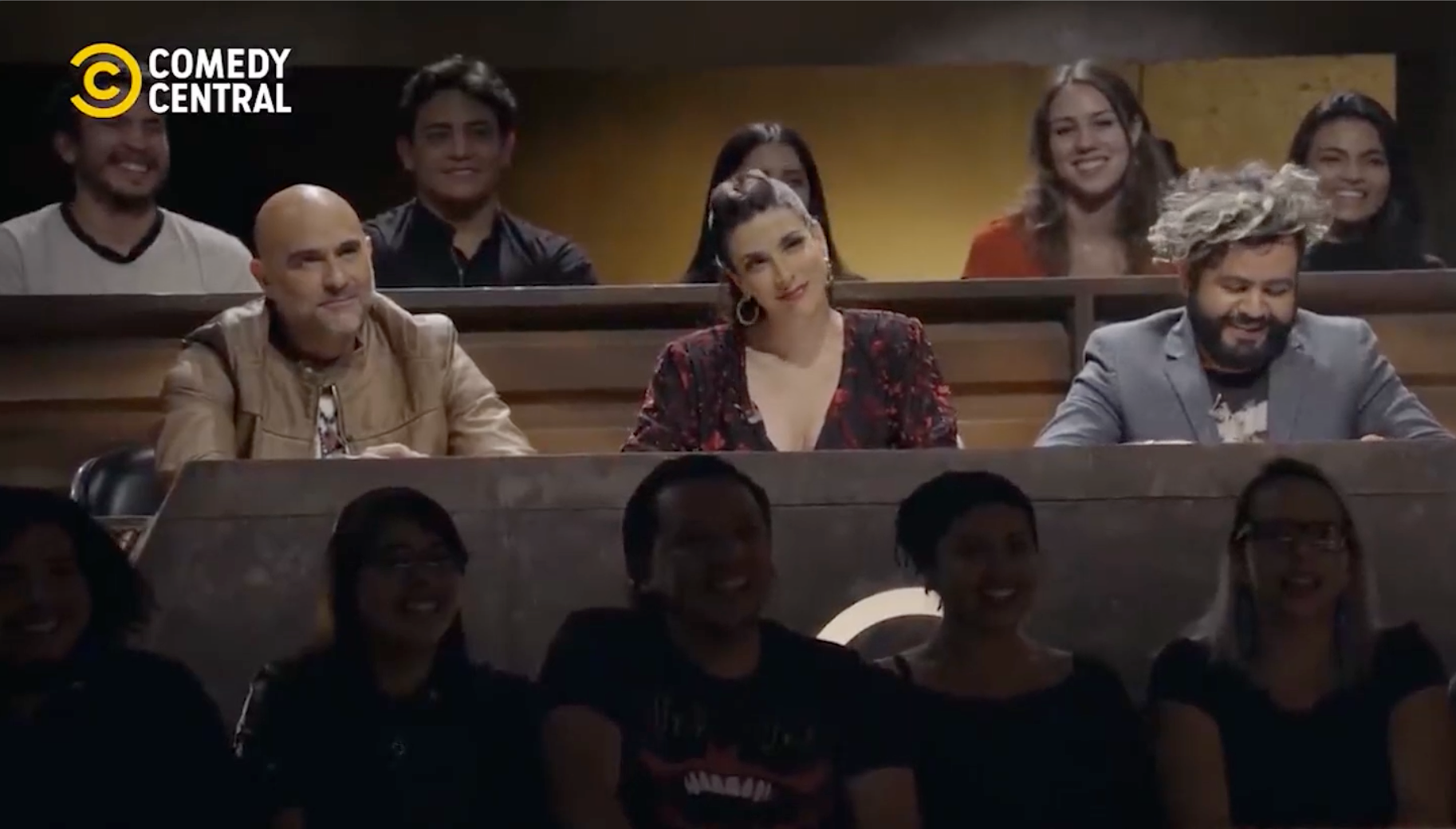 Un grupo de personas está sentado en una audiencia central de comedia.