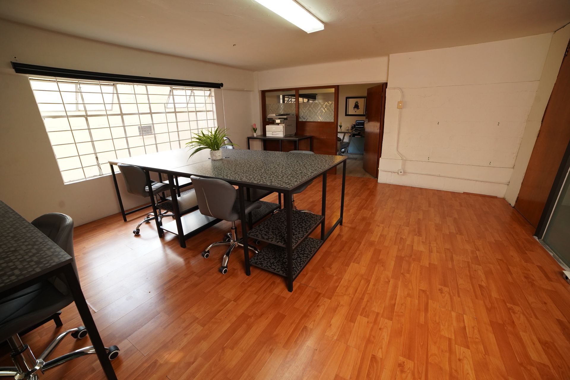 Una habitación grande con pisos de madera y una mesa y sillas.
