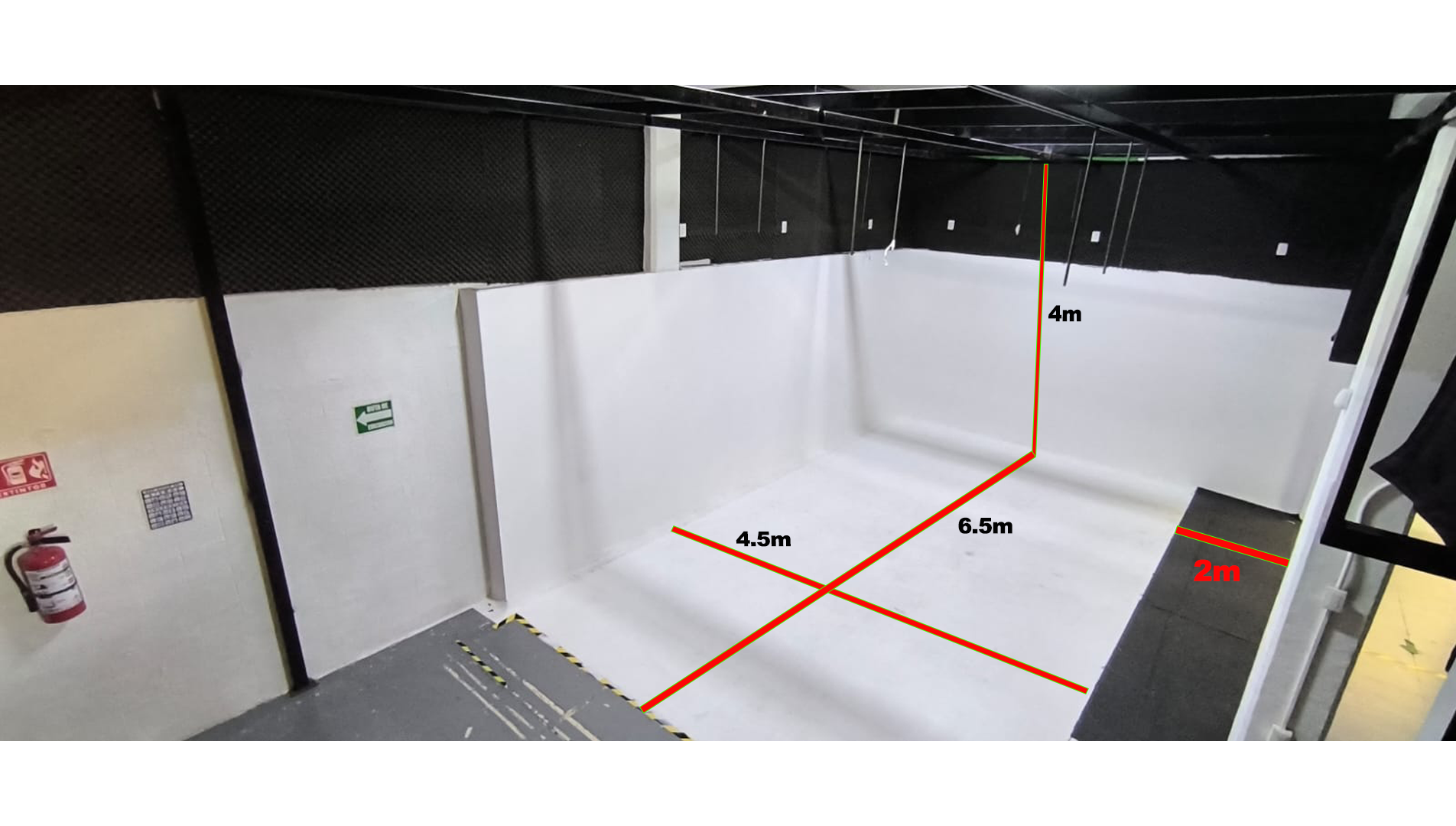 Una habitación con un extintor en la pared y una línea roja en el suelo.