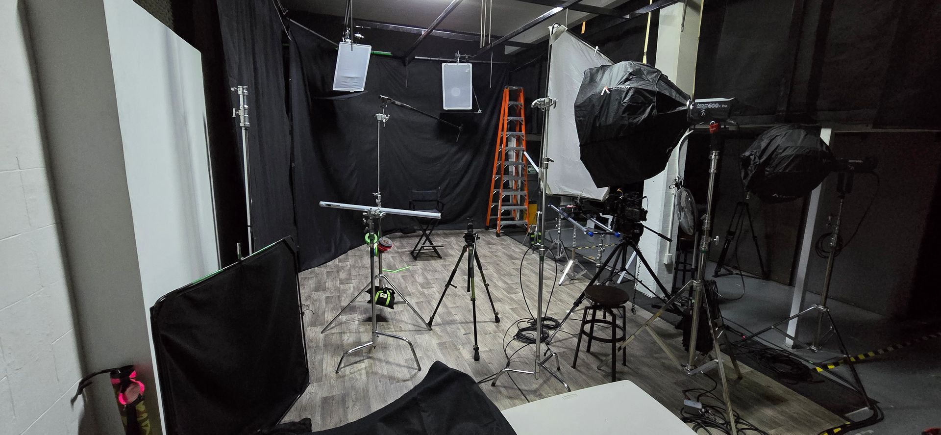 Un estudio fotográfico con mucho equipamiento y una escalera.