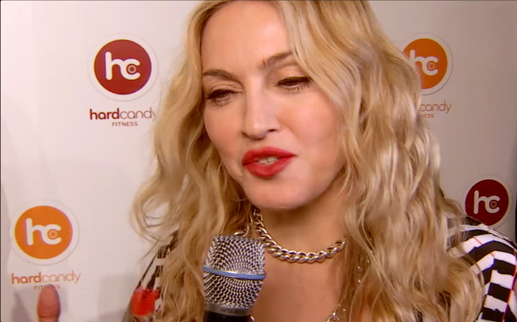 Una mujer con cabello rubio está hablando por un micrófono.