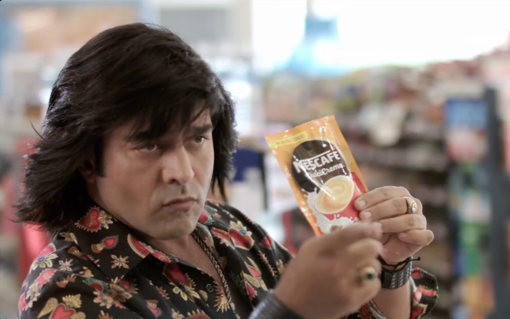Un hombre con pelo largo sostiene una bolsa de Nescafé.