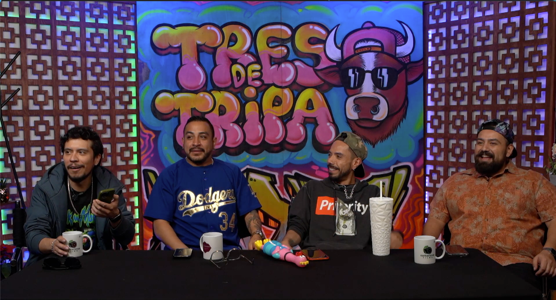 Un grupo de hombres está sentado en una mesa frente a una pared de graffitis.