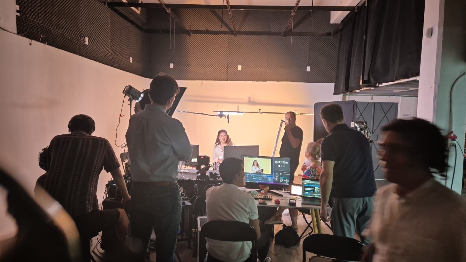 Un grupo de personas está de pie en una habitación frente a una cámara.