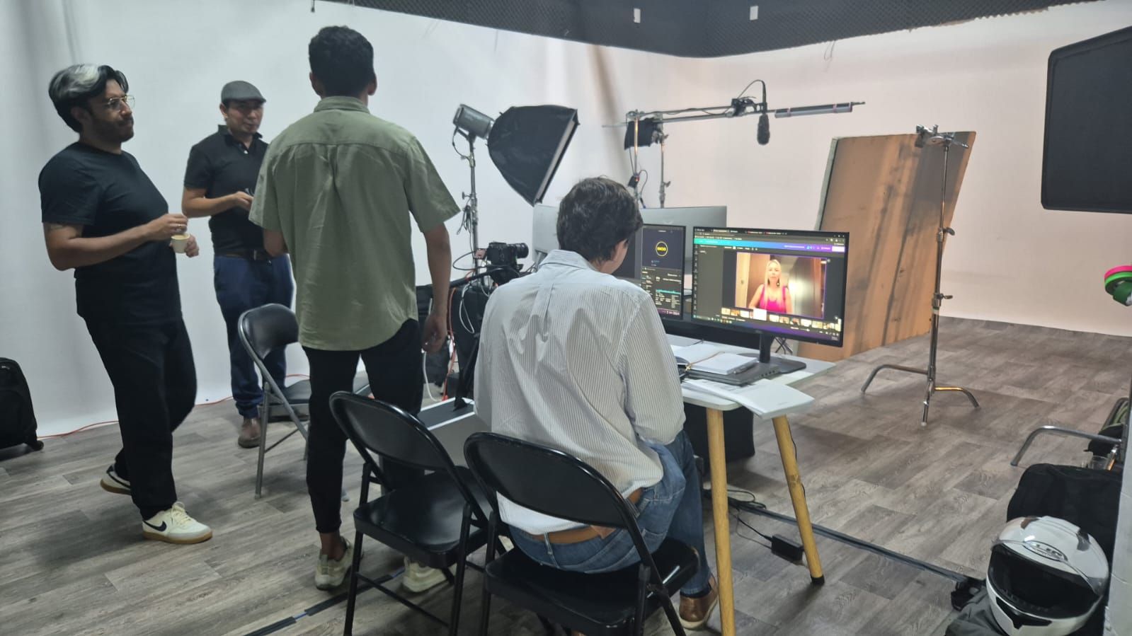 Un grupo de personas está de pie alrededor de una computadora en un estudio.