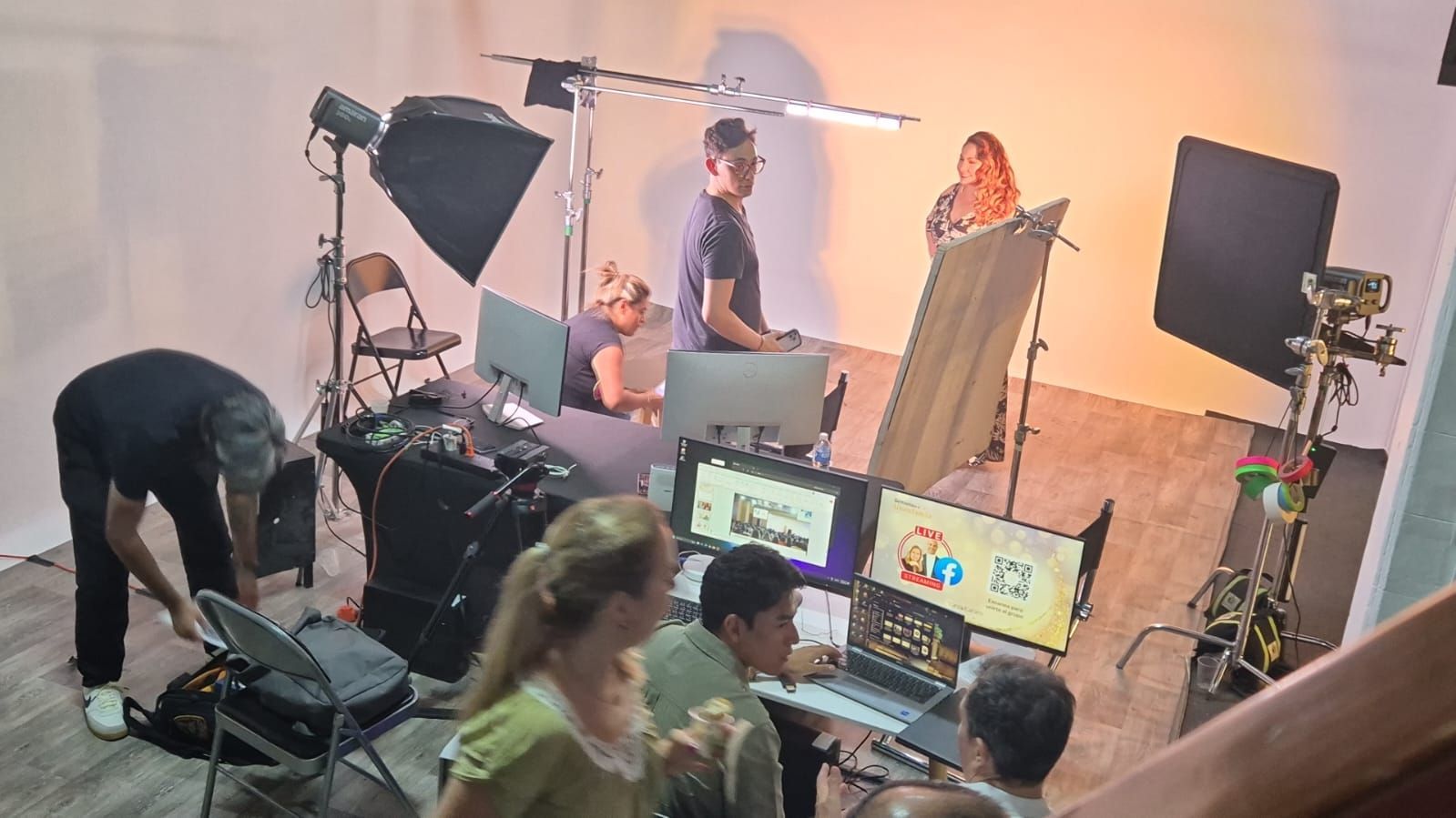 Un grupo de personas están sentadas frente a monitores de computadora en una habitación.