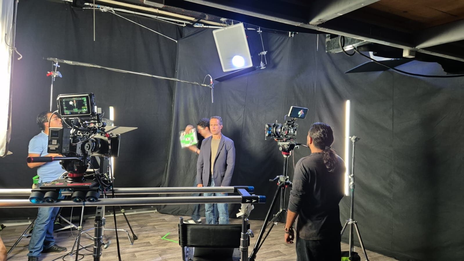 Un hombre está parado frente a una cámara en una habitación oscura.