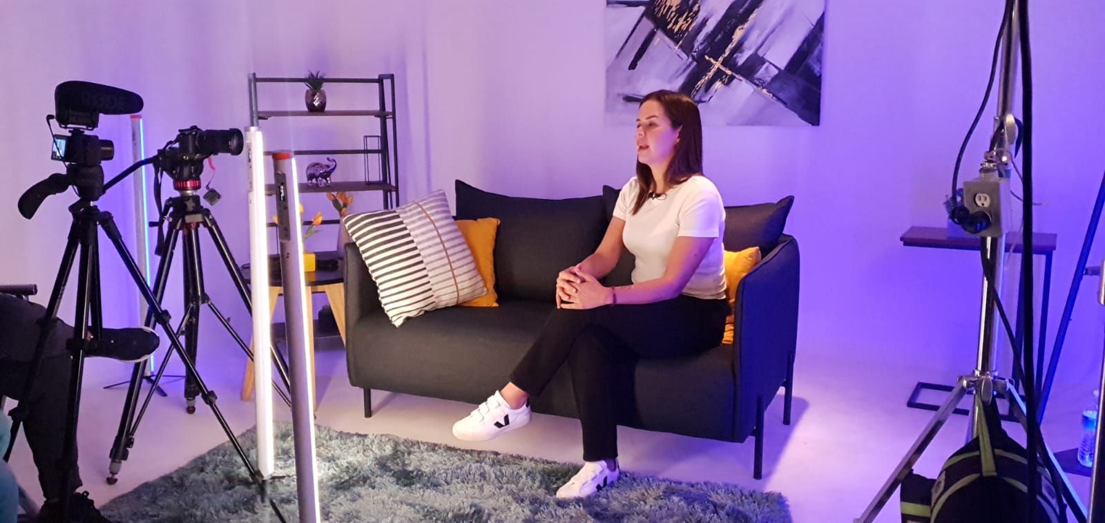 Una mujer está sentada en un sofá frente a una cámara en una habitación.