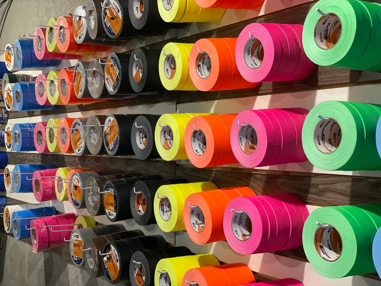 Una pared llena de rollos de cinta adhesiva de diferentes colores.