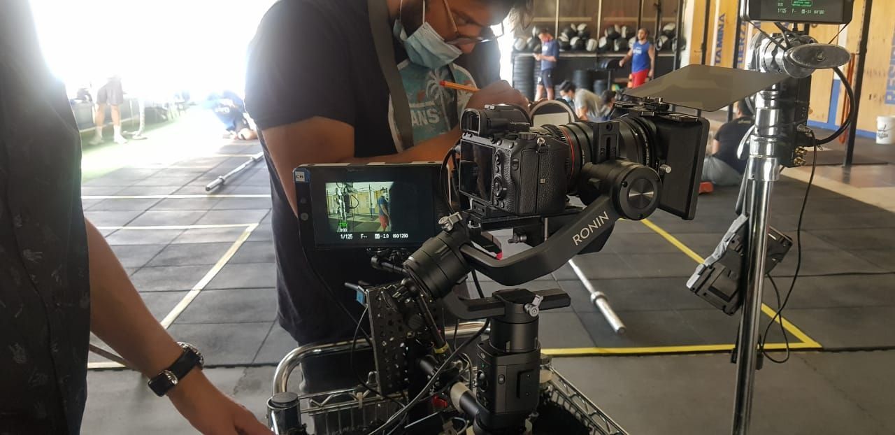 Un hombre está ajustando una cámara en un trípode en un gimnasio.