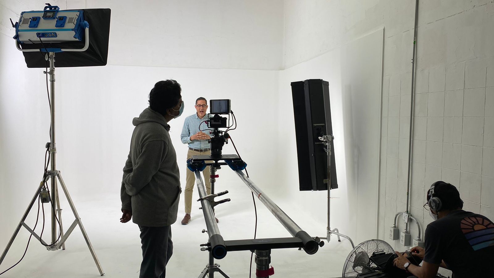 Dos hombres están parados frente a una cámara en una habitación blanca.