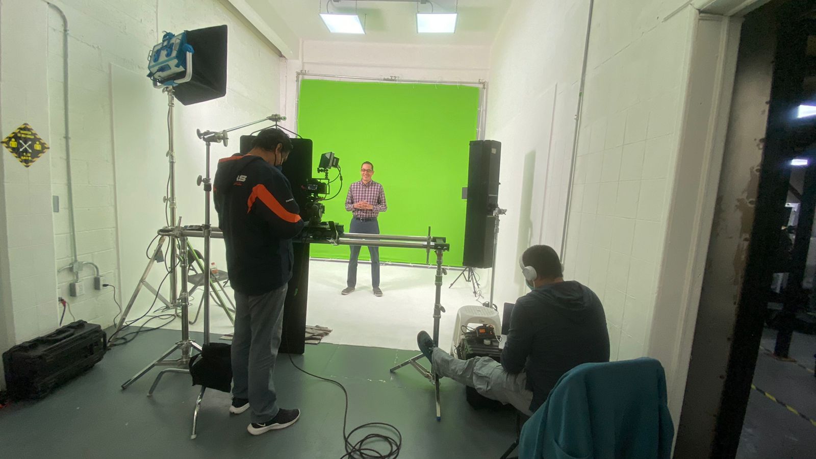 Un hombre está parado frente a una pantalla verde en un estudio.