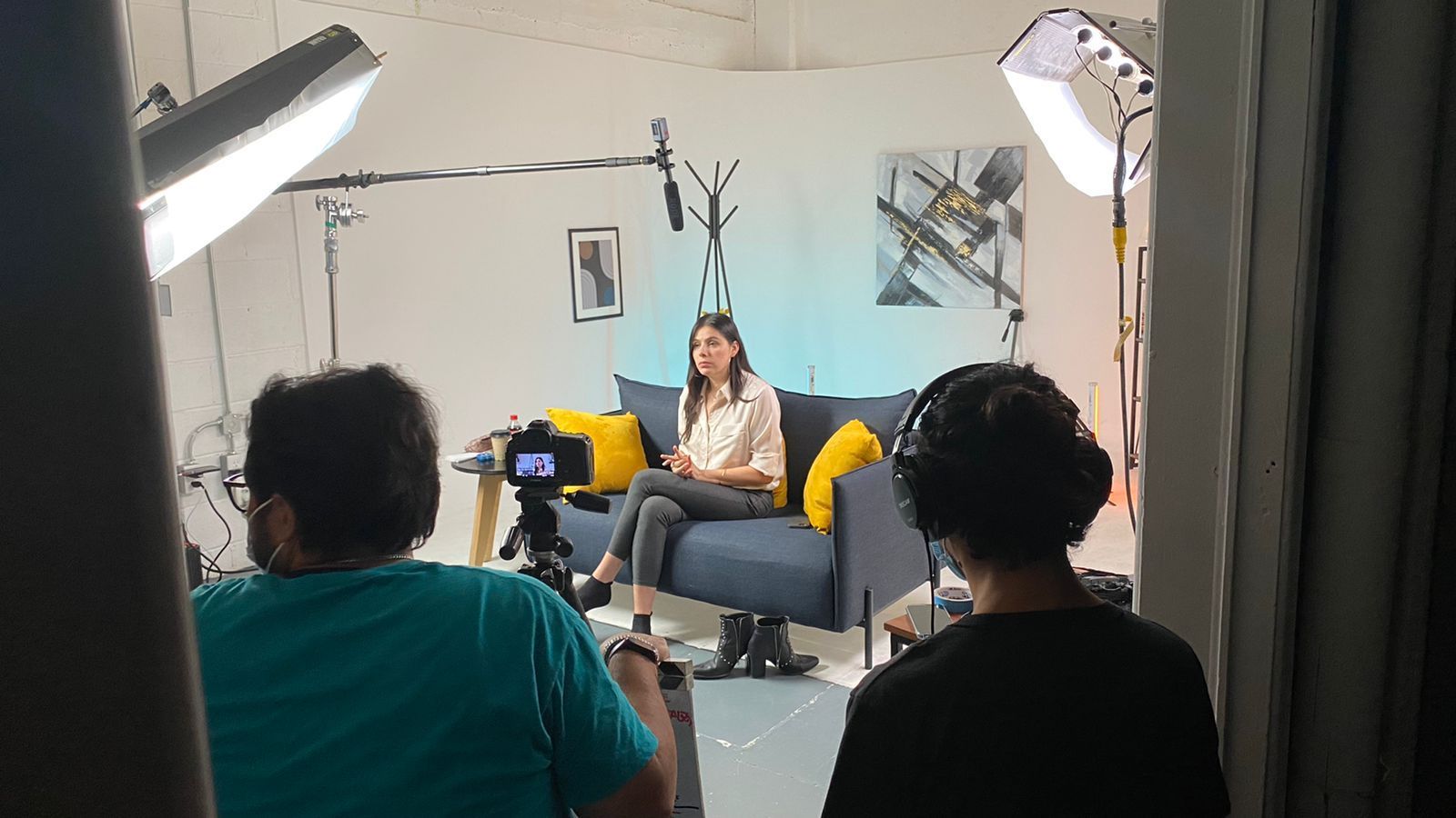 Una mujer está sentada en un sofá frente a una cámara.