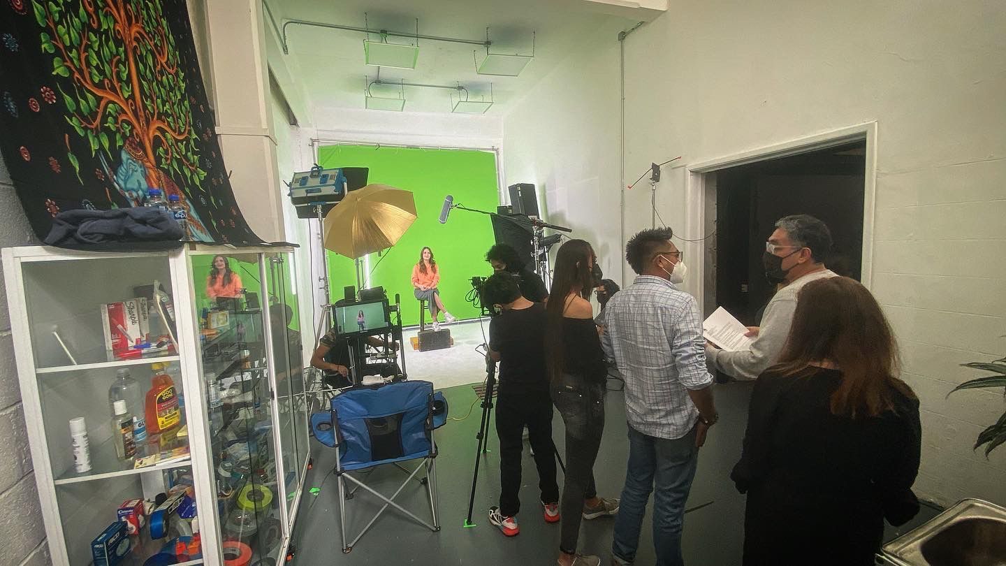 Un grupo de personas está de pie en una habitación frente a una pantalla verde.