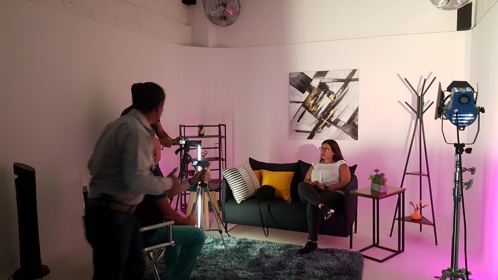 Un hombre está tomando una fotografía de una mujer sentada en un sofá en una sala de estar.