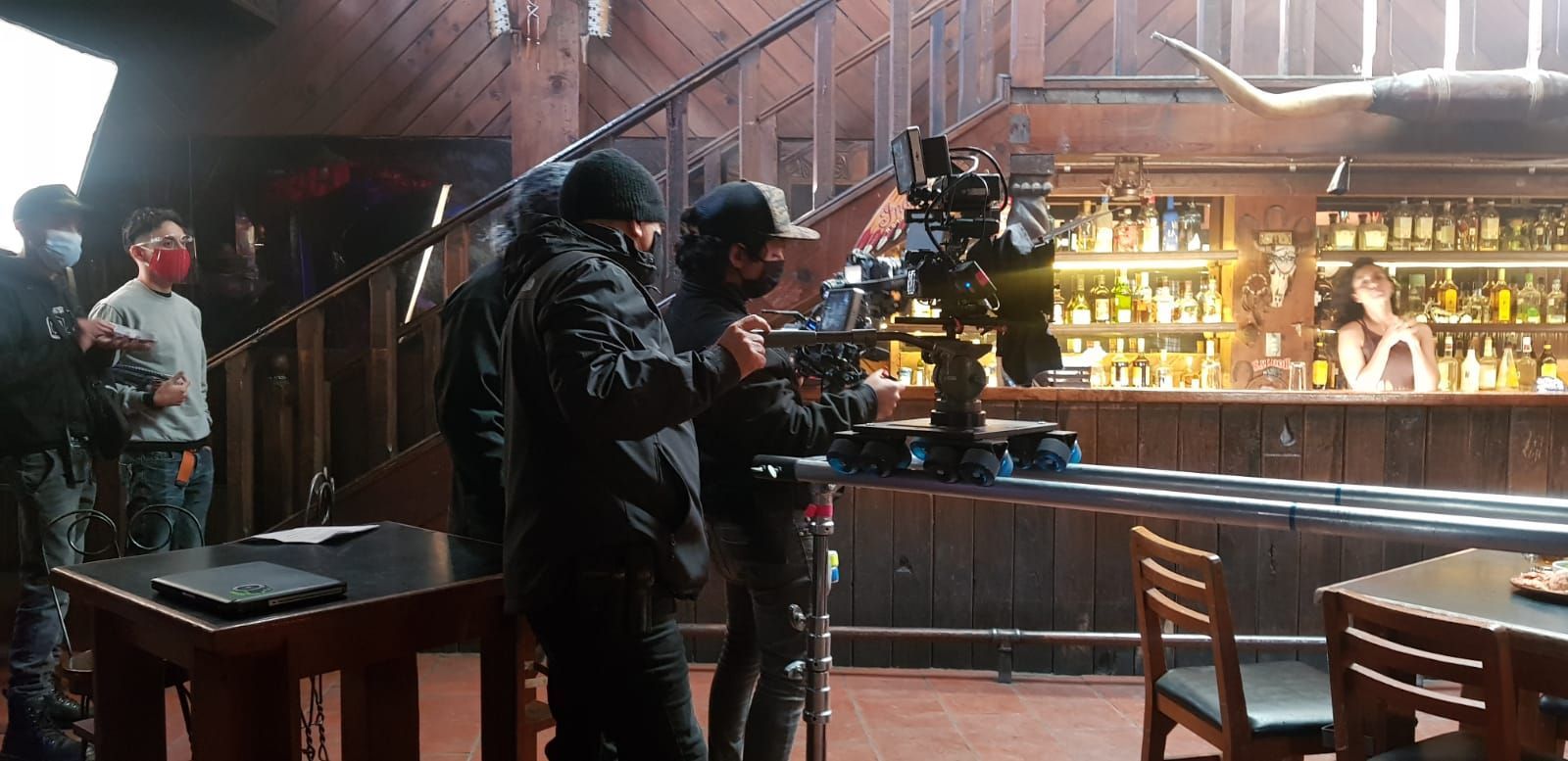 Un grupo de personas está de pie alrededor de una cámara en un bar.