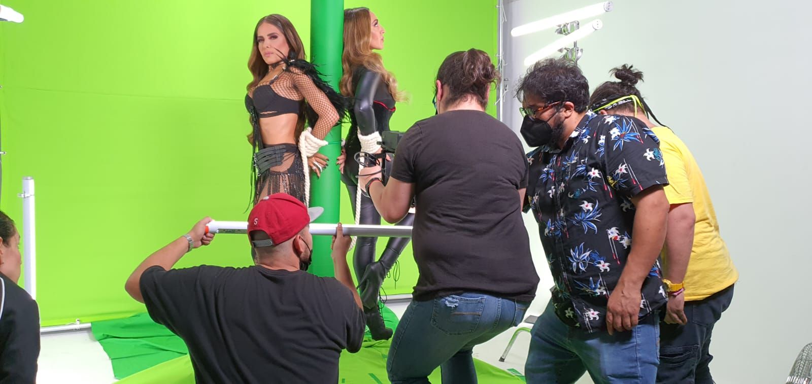 Un grupo de personas está de pie alrededor de un poste frente a una pantalla verde.