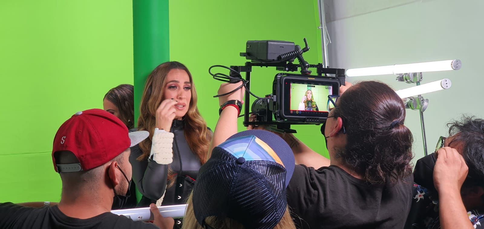 Un grupo de personas está de pie frente a una pantalla verde.