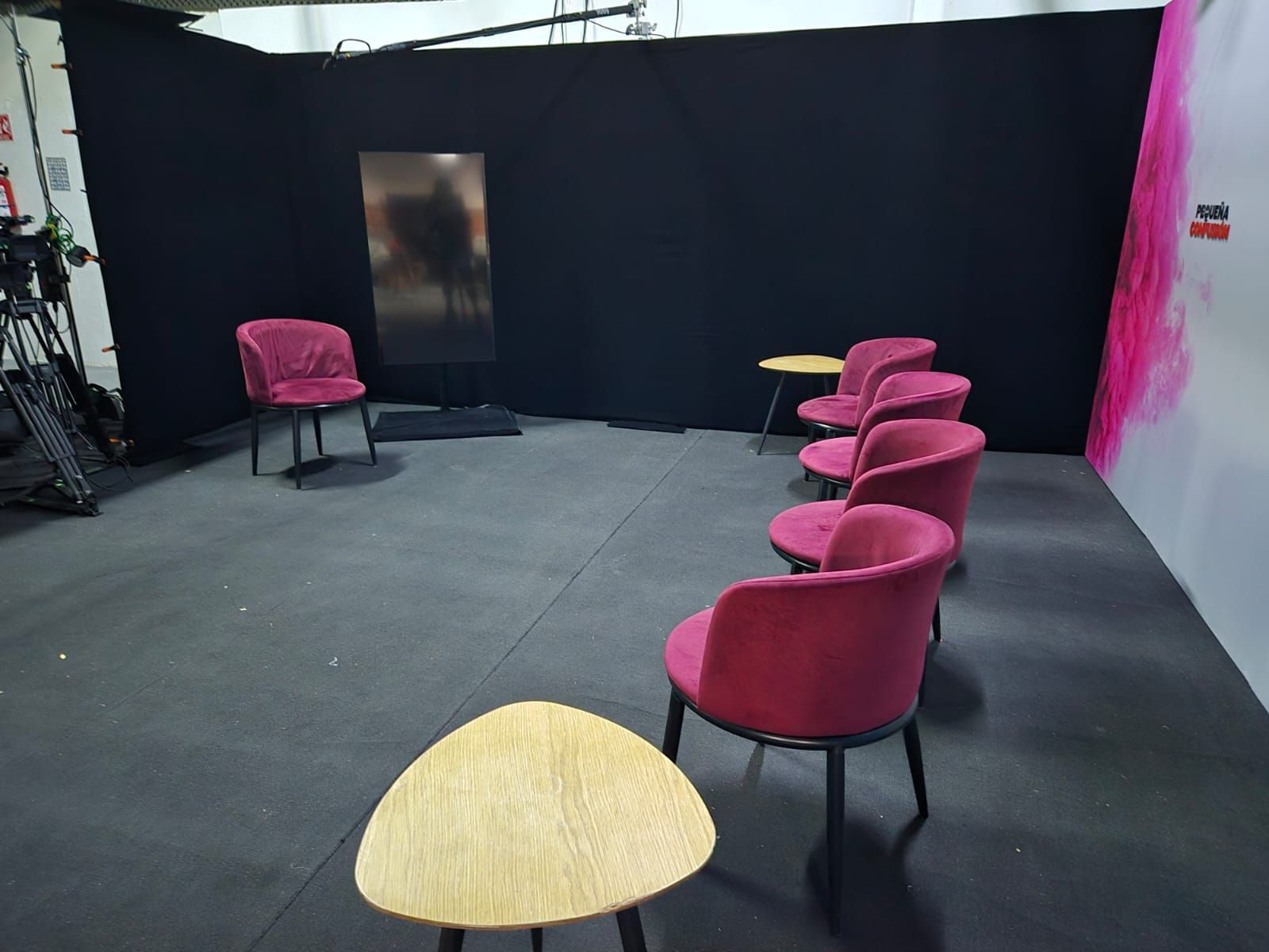 Una habitación con sillas y mesas y una pared negra.