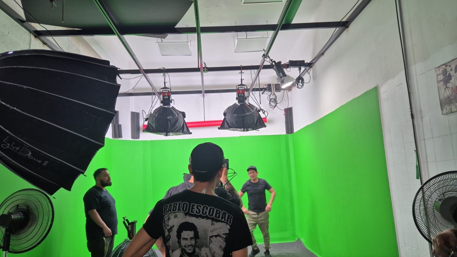 Un grupo de hombres está de pie frente a una pantalla verde en un estudio.