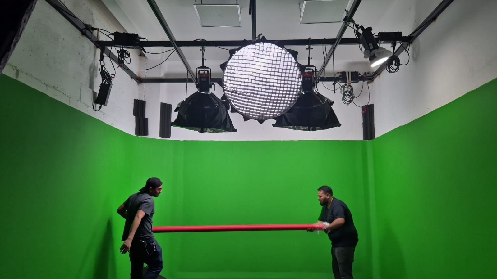 Dos hombres están parados frente a una pantalla verde en un estudio.