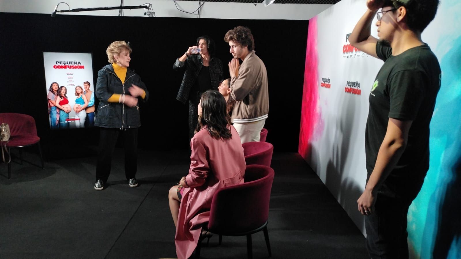 Un grupo de personas está de pie alrededor de una mujer sentada en una silla en una habitación.