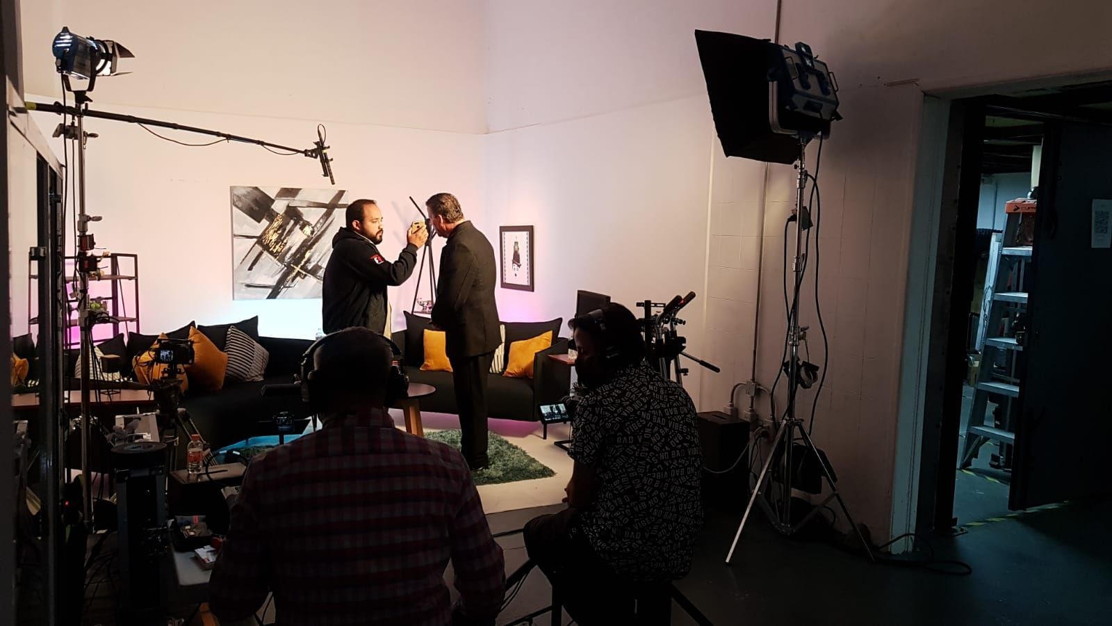 Un grupo de personas está de pie en una sala de estar frente a una cámara.