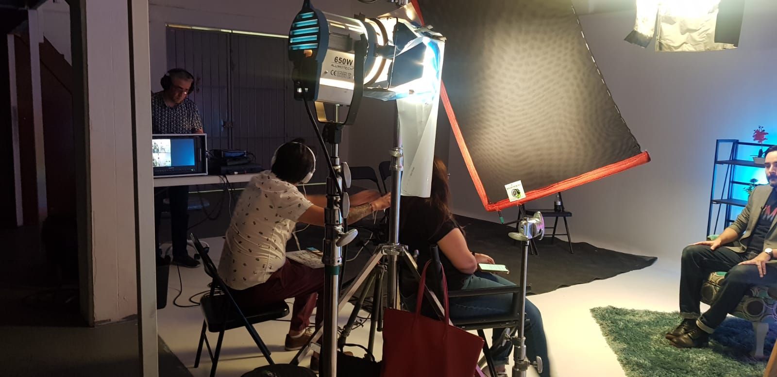 Un grupo de personas está sentada en una habitación frente a una cámara.