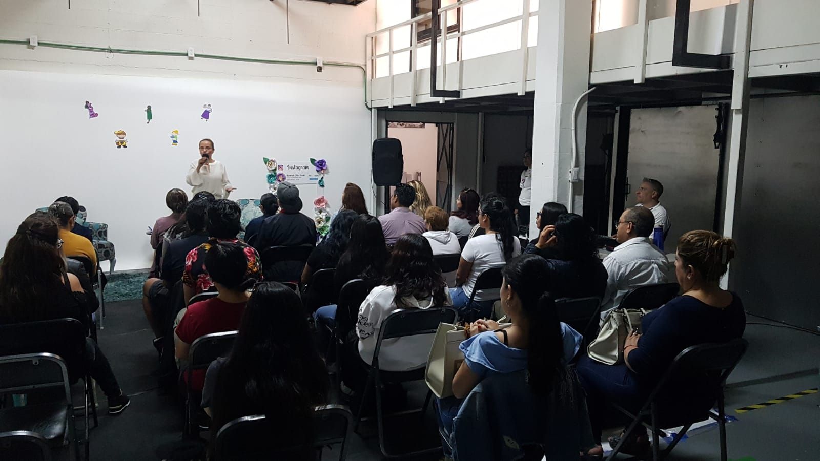 Un grupo de personas están sentadas en sillas en una habitación viendo una presentación.