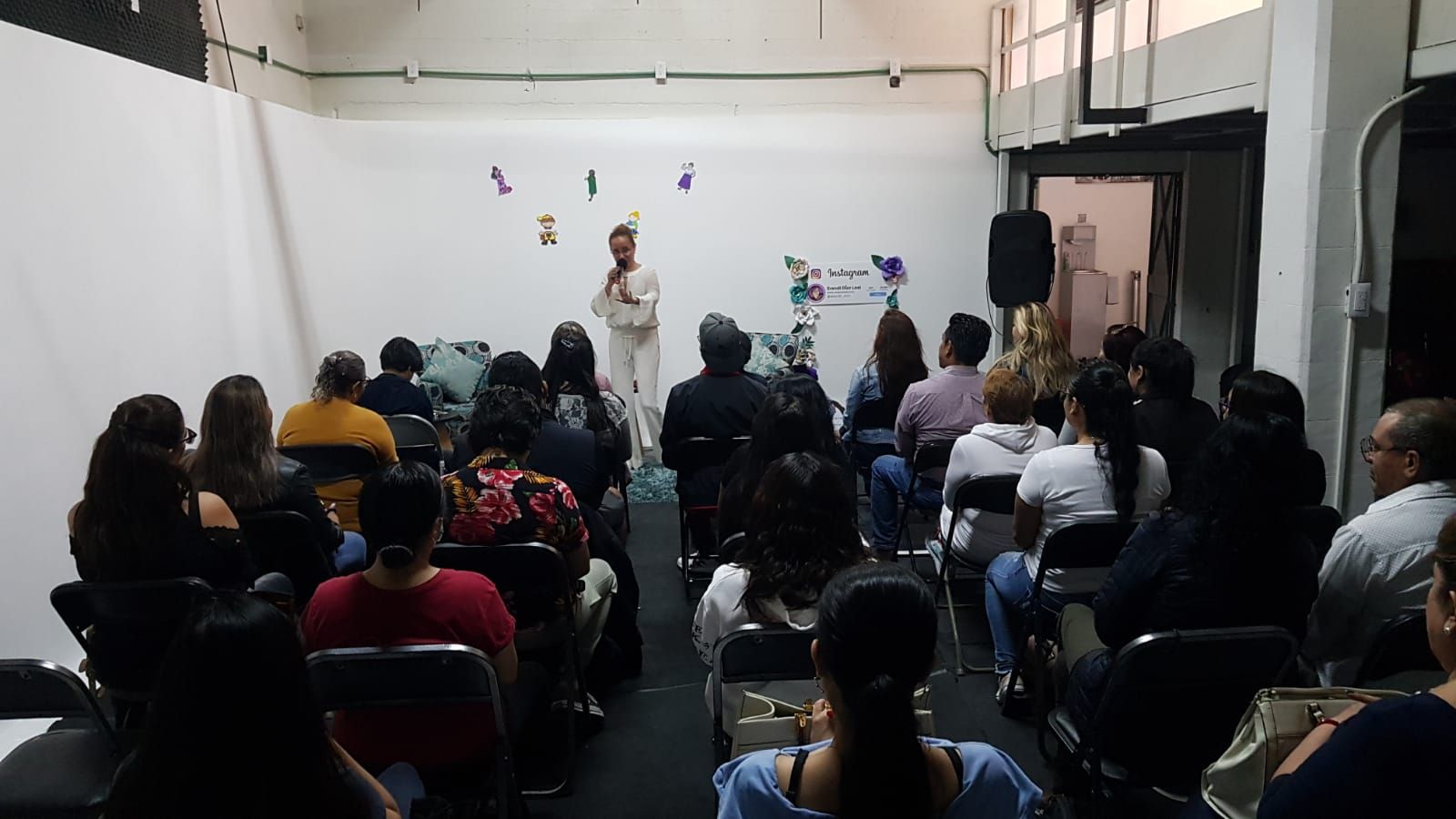Un grupo de personas están sentadas en sillas frente a un orador.