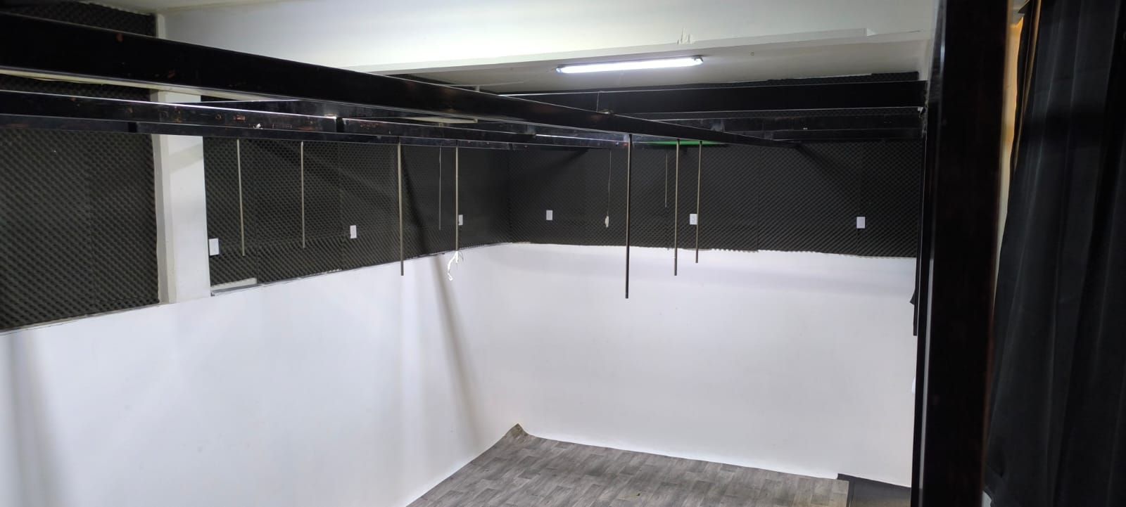 Una habitación vacía con paredes blancas y cortinas negras.