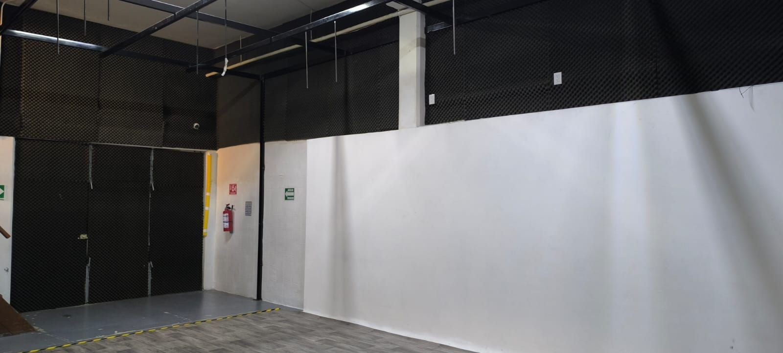 Una gran habitación vacía con paredes blancas y puertas negras.