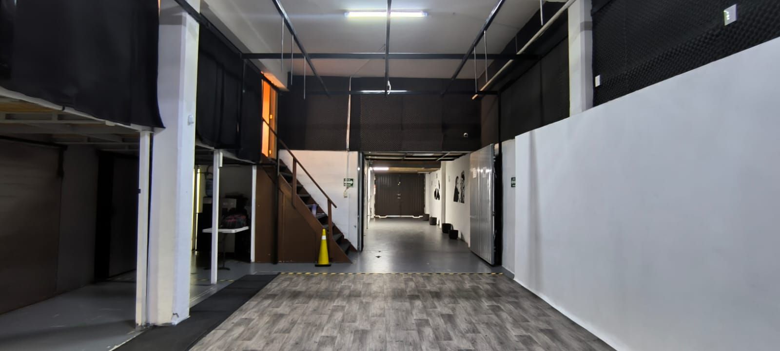 Una gran habitación vacía con suelo de madera y paredes blancas.