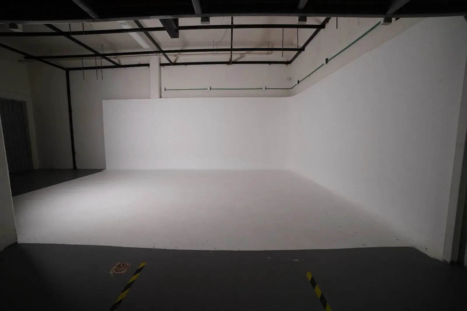 Una gran habitación vacía con paredes blancas y suelo gris.