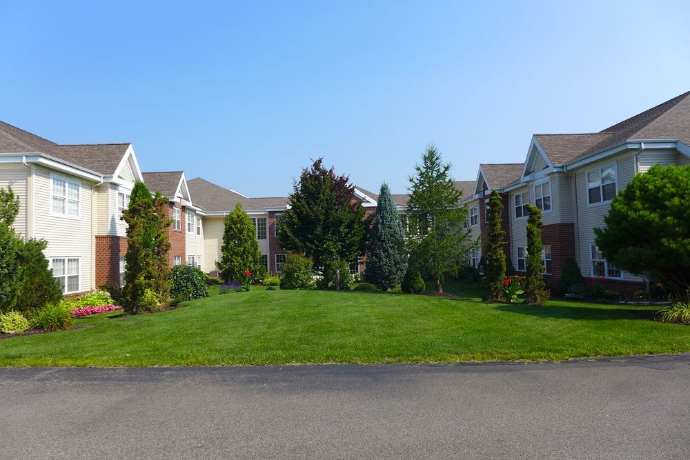 Two-story Beige Apartment Buildings With Green Lawn and Trees in Between — Property Transfer Professionals In Wyong, NSW